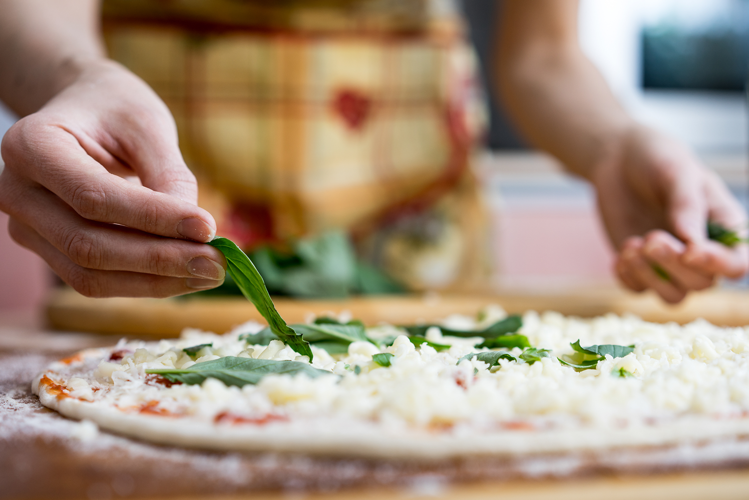 Someone Adding Basil Leaves to an Uncooked Kosher Pizza